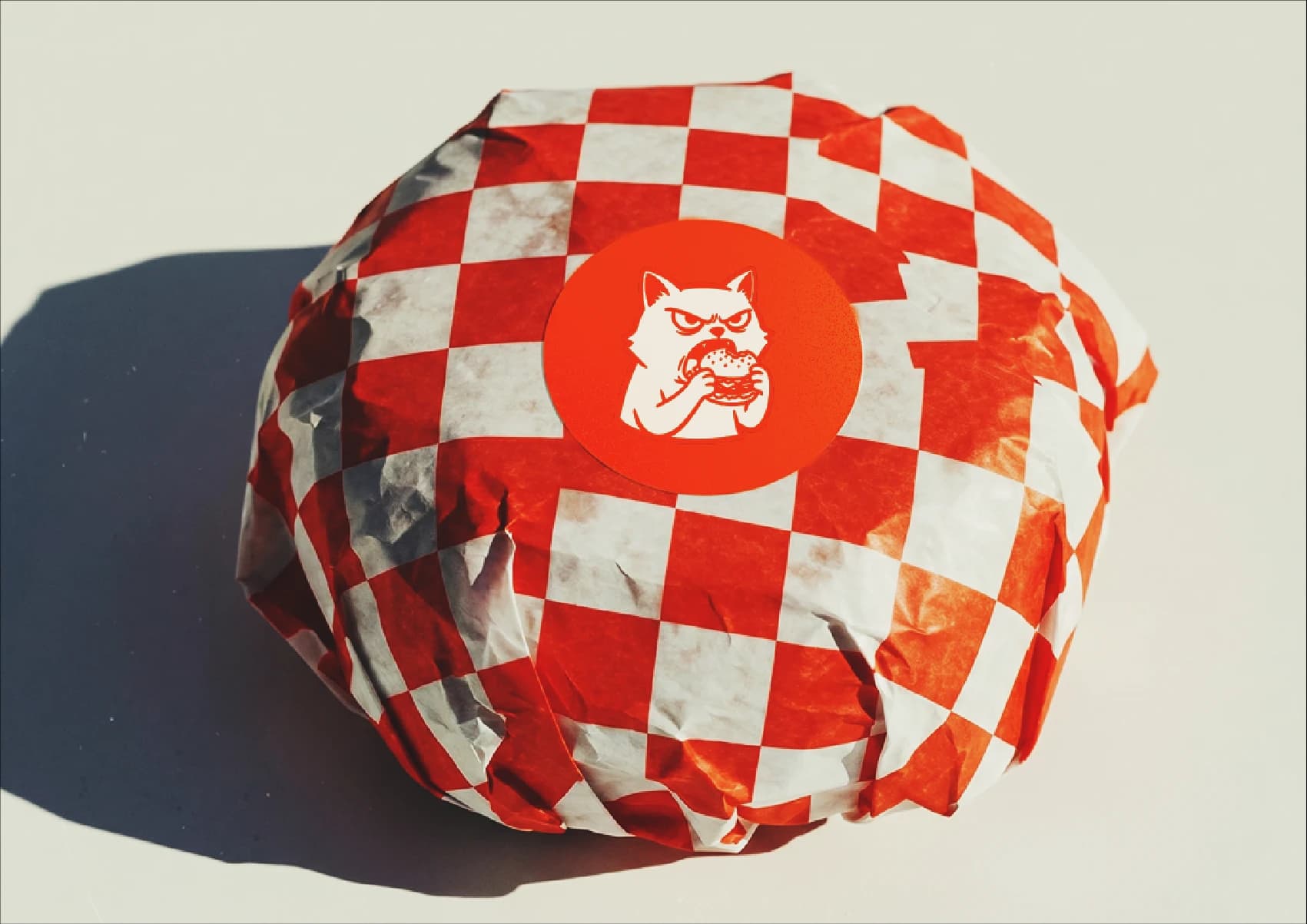 A burger in the checkerboard wrap, sealed with Mr. Cranky