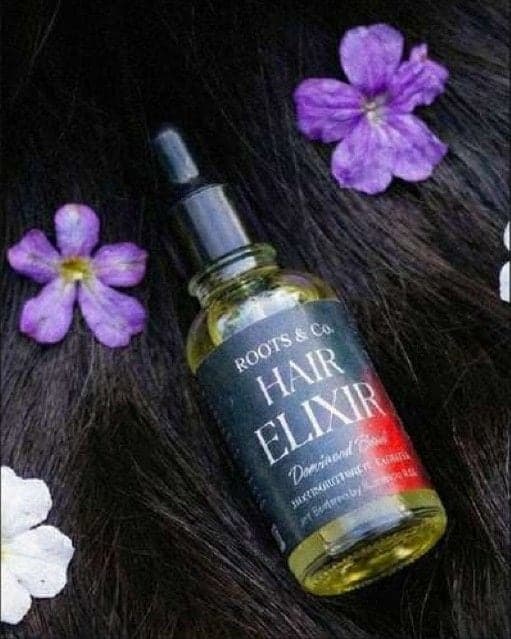 Hair Elixir bottle among flowers